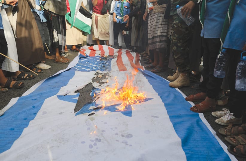  HOUTHI SUPPORTERS burn US and Israeli flags at a rally in Sana'a, on October 7. (photo credit: KHALED ABDULLAH/REUTERS)