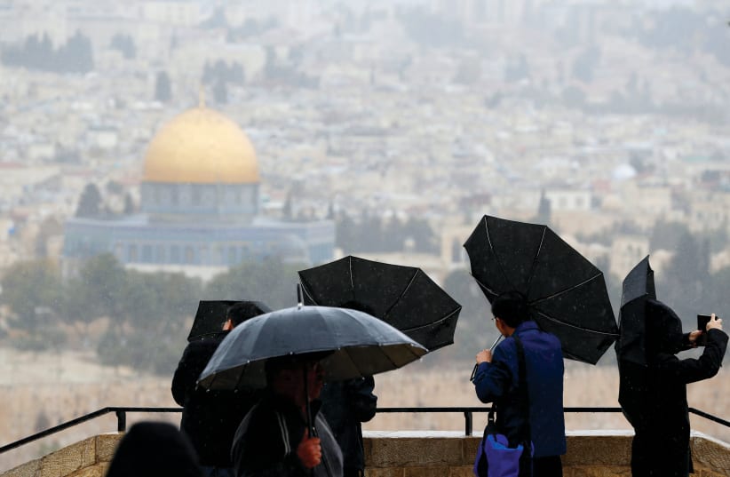  Tourists hold umbrellas as it rains on an observation point overlooking Jerusalem’s Old City. (photo credit: AMMAR AWAD/REUTERS)