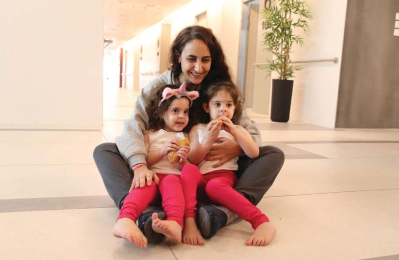  SHARON ALONI-CUNIO, 34, holds her twins Yuli Cunio, 3, and Emma Cunio, 3, at Schneider Children’s Medical Center after their release by Hamas. (photo credit: Schneider Children’s Medical Center/Reuters)