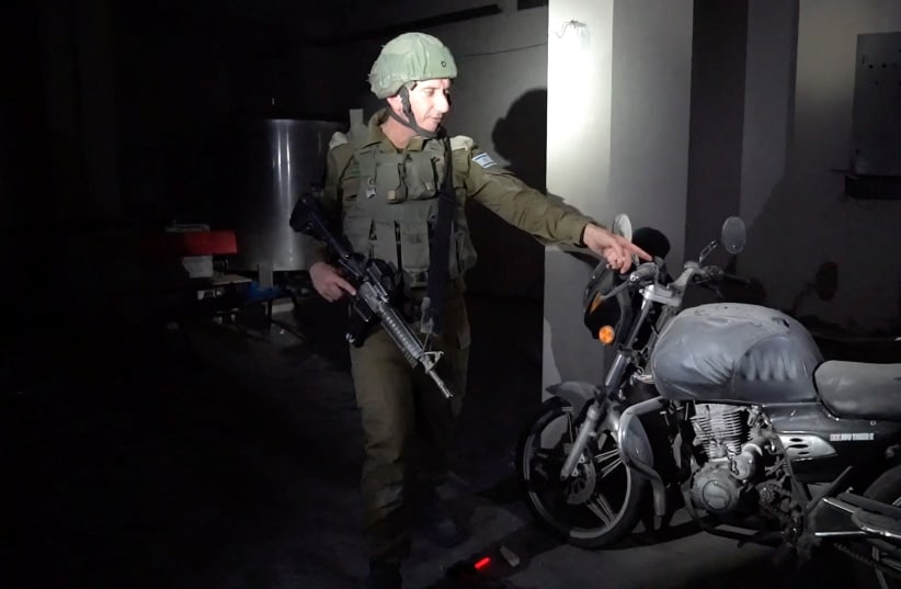  Israeli military spokesperson Rear Admiral Daniel Hagari points at a motorcycle with gunshot marks which he said appeared to have been used to bring hostages to Gaza after the surprise attack on October 7 (photo credit: REUTERS/IDF HANDOUT)