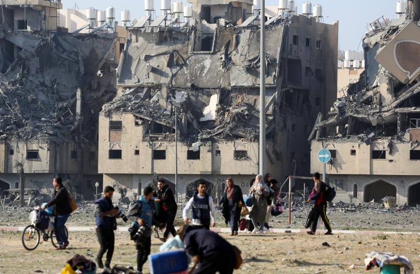 Buildings lie in ruin as Palestinians carry their belongings following Israeli strikes on residential buildings at the Qatari-funded Hamad City, amid the ongoing conflict between Israel and the Palestinian terrorist group Hamas, in Khan Younis in the southern Gaza Strip December 2, 2023.  (photo credit: Ahmed Zakot/Reuters)