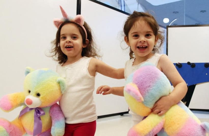  Twins Yuli Cunio, 3, and Emma Cunio, 3, who were taken hostage during the October 7 attack by Hamas, hold toy bears shortly after their arrival in Israel, at Schneider Children's Medical Center of Israel in Petah Tikva, Israel, November 27, 2023 (photo credit: SCHNEIDER CHILDREN'S MEDICAL CENTER/HANDOUT VIA REUTERS )