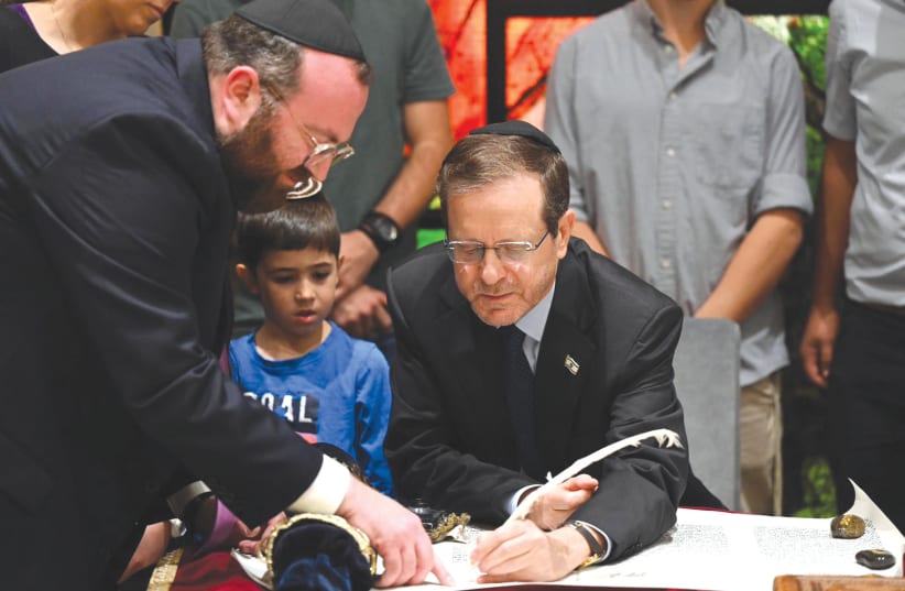  PRESIDENT ISAAC HERZOG writes a letter in a Torah scroll (photo credit: HAIM ZACH/GPO)
