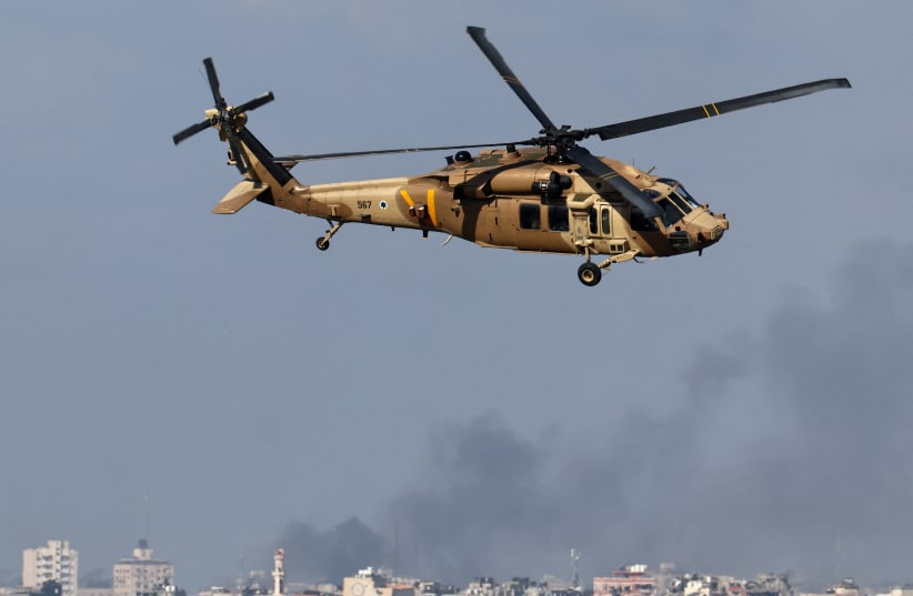  An IDF helicopter flies as smoke rises over Gaza, amid the ongoing conflict between Israel and the Palestinian Islamist group Hamas, as seen from southern Israel, December 6, 2023. (photo credit: REUTERS/ATHIT PERAWONGMETHA)
