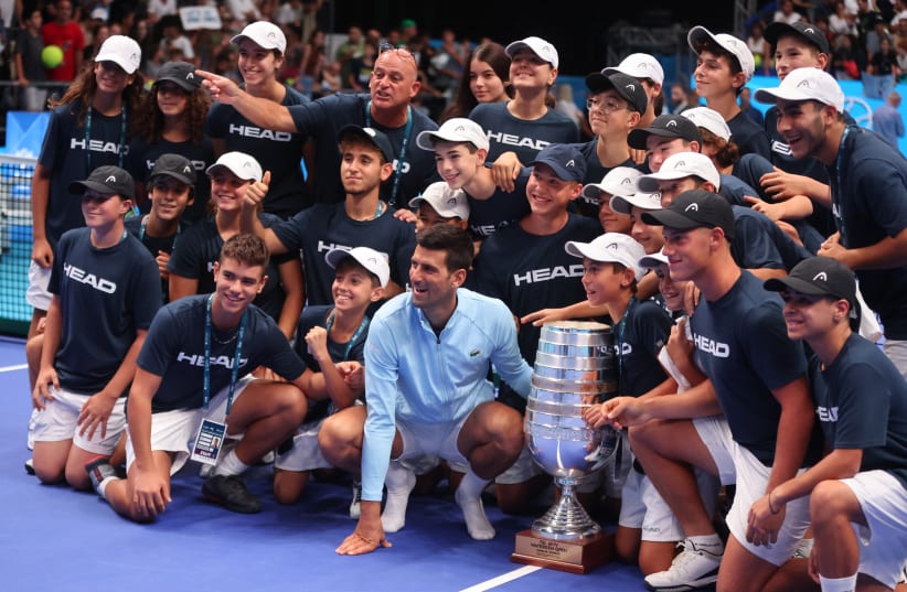  NOVAK DJOKOVIC poses with the trophy and Israeli youth tennis volunteers after winning the 2022 Tel Aviv Watergen Open, which feels like much longer than a year ago. (photo credit: NIR ELIAS/REUTERS)