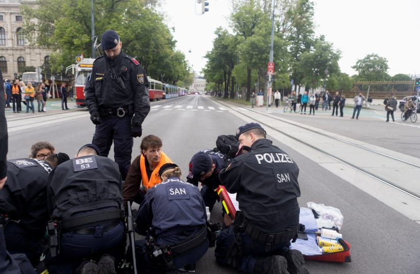 Police officers surround activists of the "Letzte Generation" (Last Generation) during a protest for a speed limit on highways as well as for affordable public transport in Vienna, Austria May 16, 2023. (photo credit: Nina Riggio/Reuters)