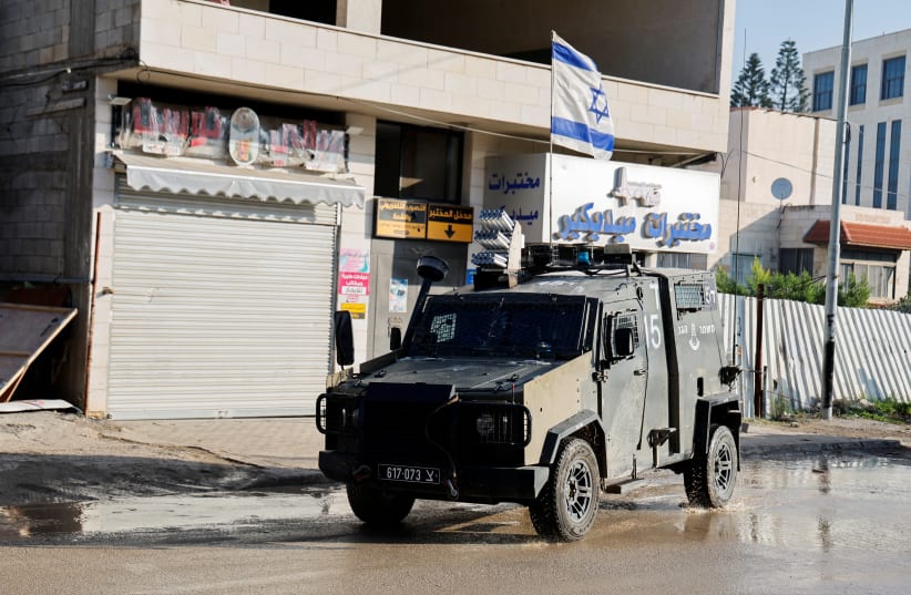  An Israeli military vehicle with an Israeli flag on top, manoeuvers on a road during a raid, amid the ongoing conflict between Israel and the Palestinian terror group Hamas, in Jenin, (photo credit: RANEEN SAWAFTA/REUTERS)