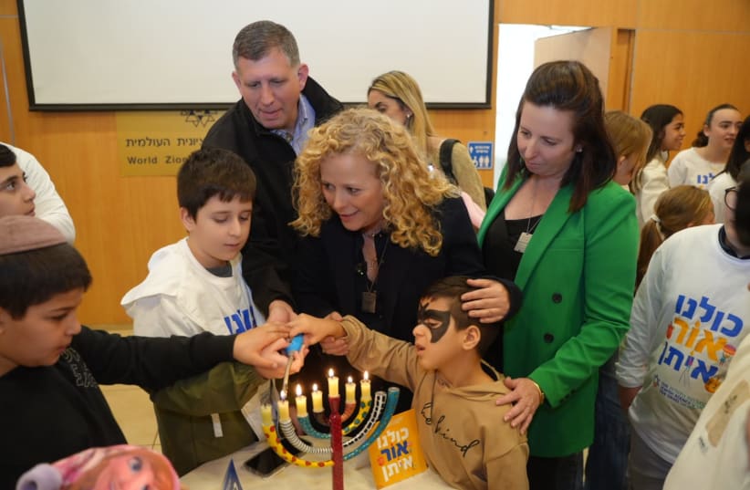  Edna Weinstock-Gabbay, CEO of Keren Hayesod, Ayelet Nahmias Verbin, Chairman of the Fund for Victims of Terror, and Sam Grundwerg Global Chairman, Keren Hayesod, light Hanukkah candles together with children at camp (photo credit: LIOR DASKAL)