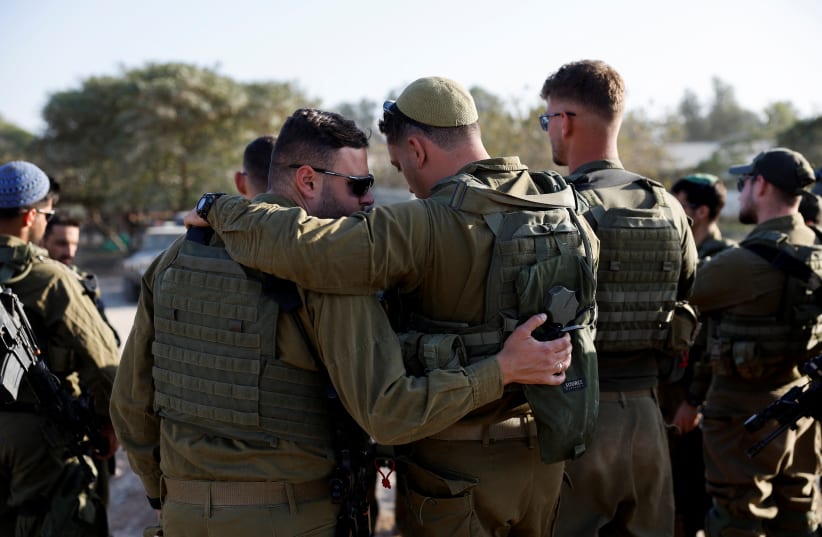  IDF soldiers embrace during briefing as they gather on the Israeli side of the Israel-Gaza border, amid the ongoing conflict between Israel and the Palestinian Islamist group Hamas, Israel December 11, 2023. (photo credit: AMIR COHEN/REUTERS)