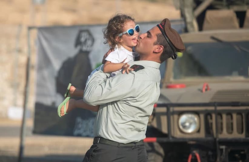  LT.-COL. TOMER GRINBERG kisses his thrilled daughter at the ceremony in which he took over as commander of the Golani Brigade’s 13th Battalion, in July.  (photo credit: IDF)