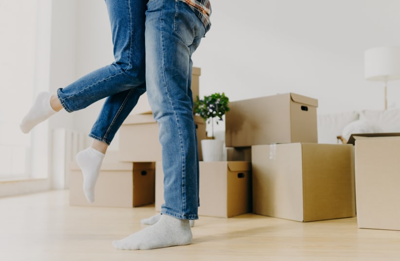  An illustrative image of newlyweds hugging as they are surrounded by boxes in their new home. (photo credit: INGIMAGE)
