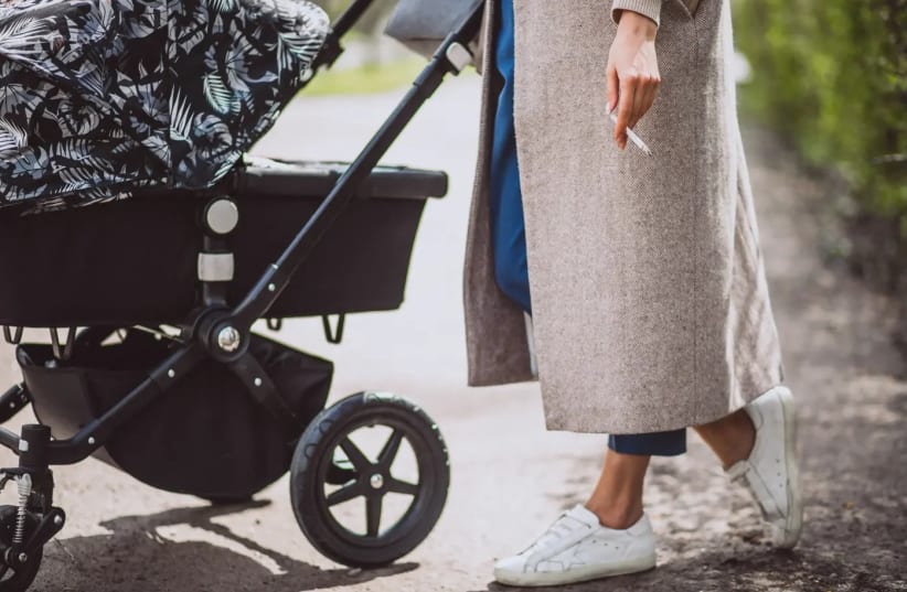 A young mother with a cigarette and a baby stroller (photo credit: SHUTTERSTOCK)