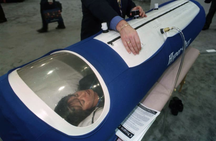  Jennifer Johnson tries out a portable hyperbaric oxygen chamber at the Super Show, the sporting goods industry's largest trade show at the World Congress Center in Atlanta. (photo credit: REUTERS)