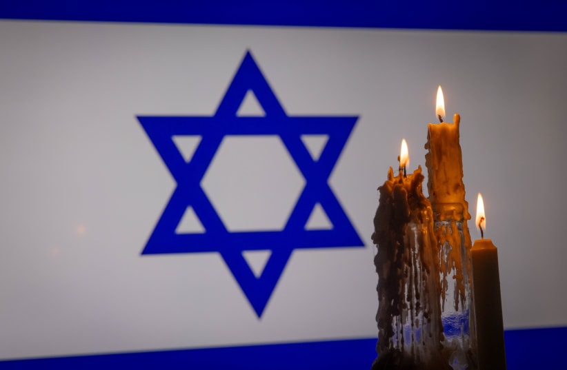 An illustration of lit candles and in the background the Israeli flag on December 17, 2023 (photo credit: Chaim Goldberg/Flash90)