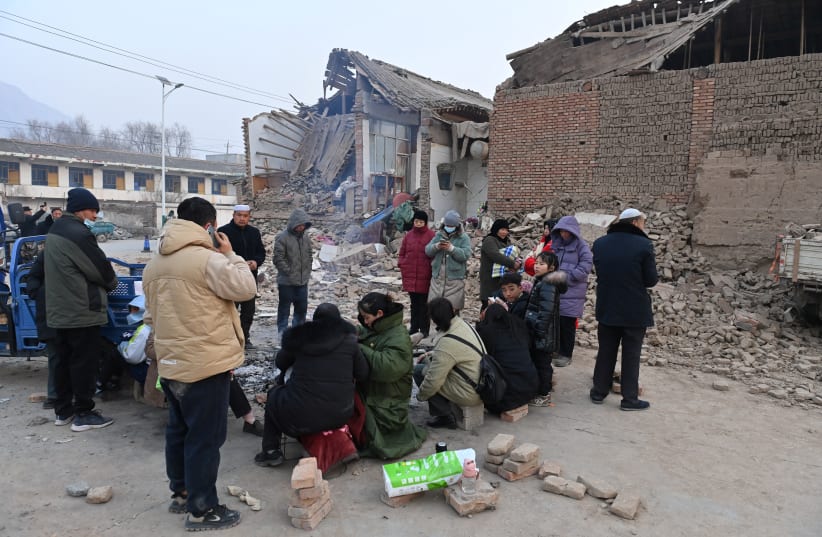  Residents keep warm by a fire next to damaged buildings at Dahejia town following the earthquake in Jishishan county, Gansu province, China December 19, 2023. (photo credit: CNSPHOTO VIA REUTERS)