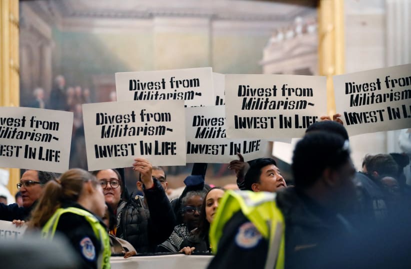 People display signs, chant, and sing as they await arrest during a protest in the US Capitol rotunda to call for a permanent ceasefire in Gaza and oppose a military aid package for Israel, in Washington, US December 19, 2023. (photo credit: REUTERS/Allison Bailey)