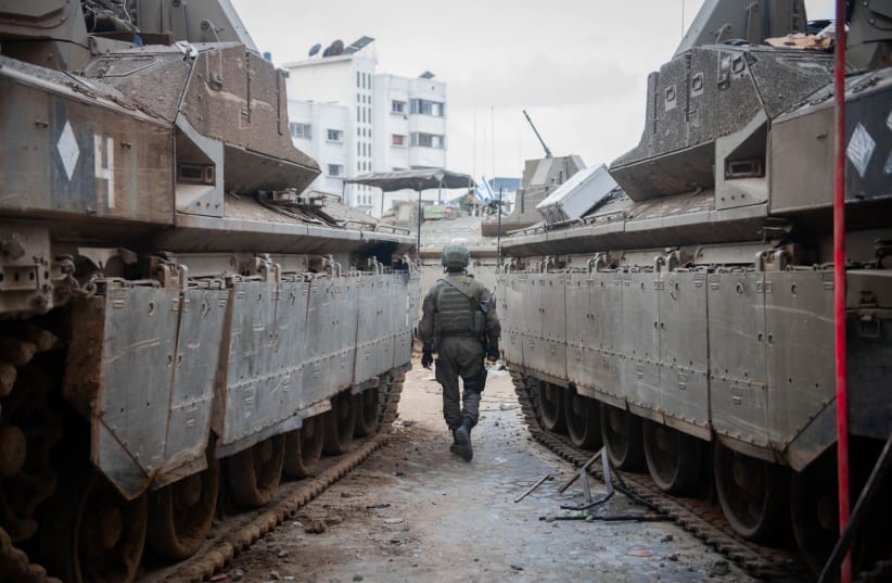  IDF soldier seen walking between two armored vehicles in Gaza, December 20, 2023.  (photo credit: IDF SPOKESPERSON'S UNIT)