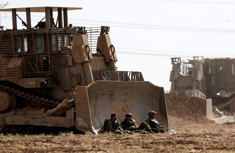 Israeli soldiers sit next to a heavy military bulldozer in an area near Israel's border with the Gaza Strip, in southern Israel October 19, 2023. (photo credit: REUTERS/Ronen Zvulun)