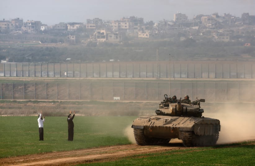  An Ultra-Orthodox Jewish man walks as an Israeli tank manoeuvres near the Gaza border, southern Israel, December 27, 2023 (photo credit: REUTERS/AMIR COHEN)