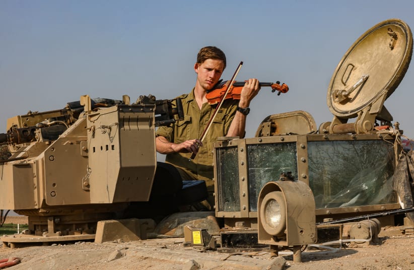  A SOLDIER plays the violin from a tank near Gaza earlier this month. Before hastily labeling Israel an apartheid state or accusing it of 'ethnic cleansing,' consider its true nature: an intricate, vulnerable democracy. (photo credit: Menahem Kahana/AFP via Getty Images)
