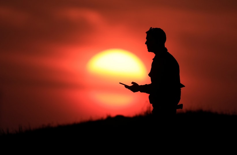 An Israeli soldier stands on a hill during sunset, December 30, 2023 (photo credit: AMIR COHEN/REUTERS)