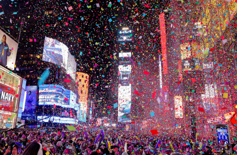  People watch confetti flying around after the clock strikes midnight during New Year celebrations at Times Square, in New York City, New York, U.S., January 1, 2024. (photo credit: REUTERS/ANDREW KELLY)