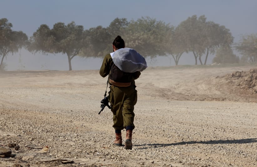  An IDF soldier walks near the Israel-Gaza border, amid the ongoing conflict between Israel and the Palestinian Islamist group Hamas, in southern Israel, December 31, 2023. (photo credit: Violeta Santos Moura/Reuters)
