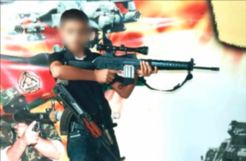 Photo of a child in Gaza holding weapons in front of a Hamas poster (photo credit: IDF SPOKESPERSON'S UNIT)