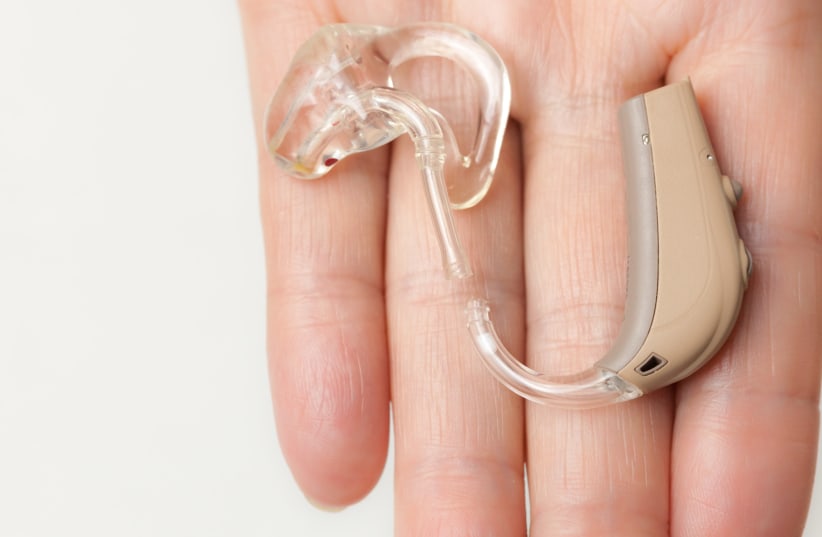  Closeup of a senior woman with an electronic hearing aid in her hand. (photo credit: INGIMAGE)