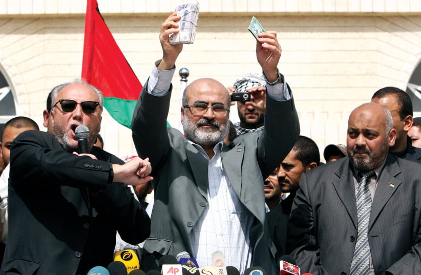  Ziad al-Zaza, then-economy minister in the Hamas government in the Gaza Strip, displays cash he received from British politician George Galloway (left) during the latter’s visit to Gaza City in 2009.  (photo credit: MOHAMMED SALEM/REUTERS)