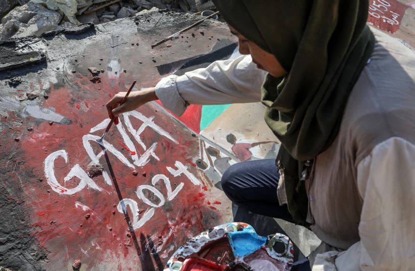 PALESTINIAN ARTIST Amal Abu Al-Sabh paints on the wall of a house destroyed by Israeli airstrikes in Rafah, on January 3, 2024. (photo credit: ABED RAHIM KHATIB/FLASH90)