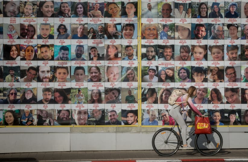  People walk by photographs of civilians held hostage by Hamas terrorists in Gaza,  in Tel Aviv. January 04, 2023.  (photo credit: MIRIAM ALSTER/FLASH90)