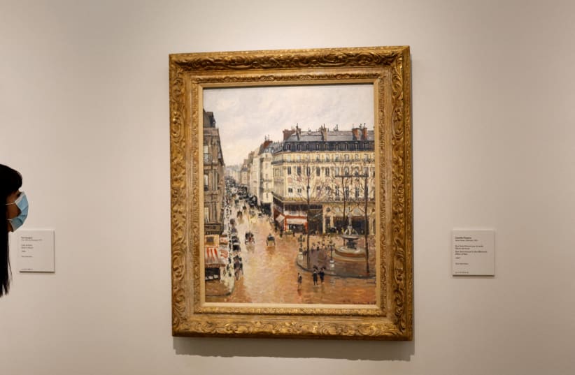  A visitor leans to look at Camille Pissarro's "Rue Saint-Honore in the Afternoon. Effect of Rain, 1897" at Thyssen-Bornemisza museum in Madrid, Spain, April 22, 2022. (photo credit: REUTERS/SUSANA VERA/FILE PHOTO)