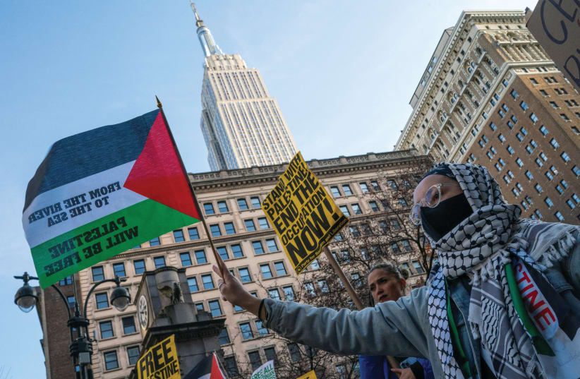  A PROTESTER holds a flag that reads: ‘From the river to the sea, Palestine will be free,’ at a march in New York City, last month. (photo credit: Eduardo Munoz/Reuters)