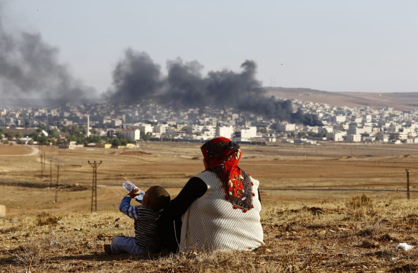 urkish Kurds watch smoke rises over Syrian town of Kobani after an airstrike, as seen from the Mursitpinar border crossing on the Turkish-Syrian border in the southeastern town of Suruc in Sanliurfa province, October 18, 2014. A U.S.-led military coalition has been bombing Islamic State fighters who (photo credit: KAI PFAFFENBACH/REUTERS)