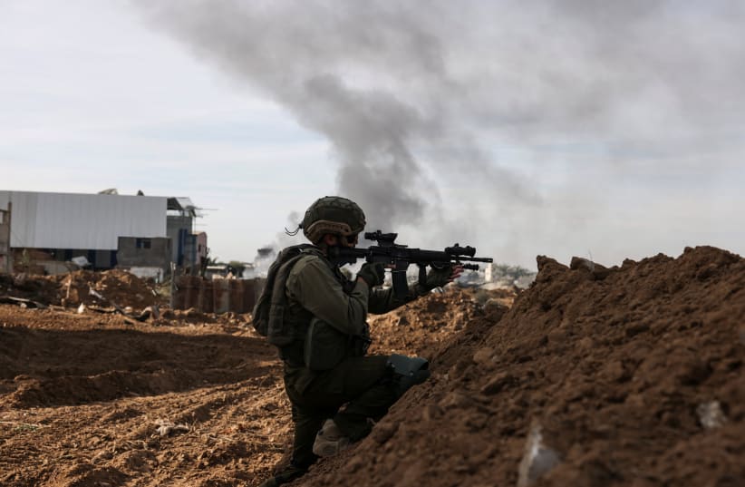  An Israeli soldier aims his weapon as he operates, amid the ongoing conflict between Israel and the Palestinian Islamist group Hamas, in Gaza, January 8, 2024.  (photo credit: REUTERS/Ronen Zvulun)