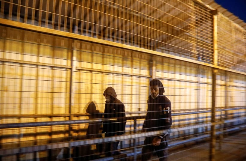  Palestinian laborers walk through an Israeli checkpoint on their way to their workplaces in Israel, Qalqilyam March 2, 2021 (photo credit: REUTERS/RANEEN SAWAFTA)