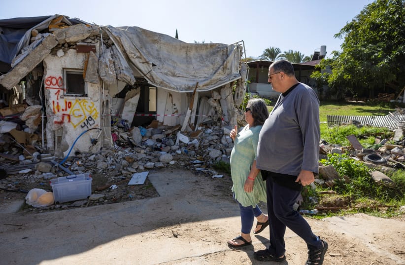  Ayelet Khon and Shar Shnurman walk past the remains of a home that was destroyed following the October 7 attack on Israel by Hamas, January 13, 2024 (photo credit: REUTERS/AMIR COHEN)