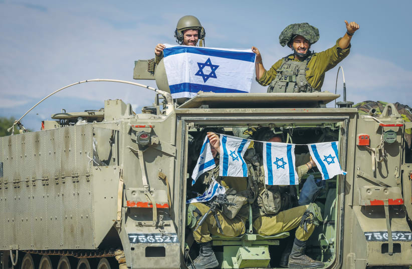  IDF SOLDIERS proudly display Israeli flags near the border with Lebanon. The Jewish people believe they deserve the right to their historic homeland, the Land of Israel, the writer asserts. (photo credit: David Cohen/Flash90)