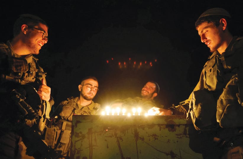  IDF soldiers light candles for Hanukkah near Israel’s border with Gaza in southern Israel on December 14, 2023.  (photo credit: AMIR COHEN/REUTERS)