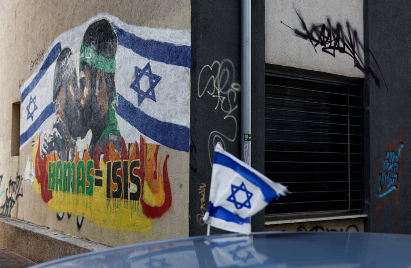  An Israeli flag flutters near anti-Hamas graffiti on the wall, in Tel Aviv (photo credit: REUTERS/TYRONE SIU)