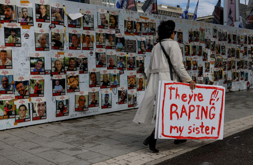 A demonstrator walks past a board displaying images of hostages kidnapped in the deadly October 7 attack on Israel by  Hamas, in Tel Aviv, Israel, January 29, 2024 (photo credit: REUTERS/TYRONE SIU)