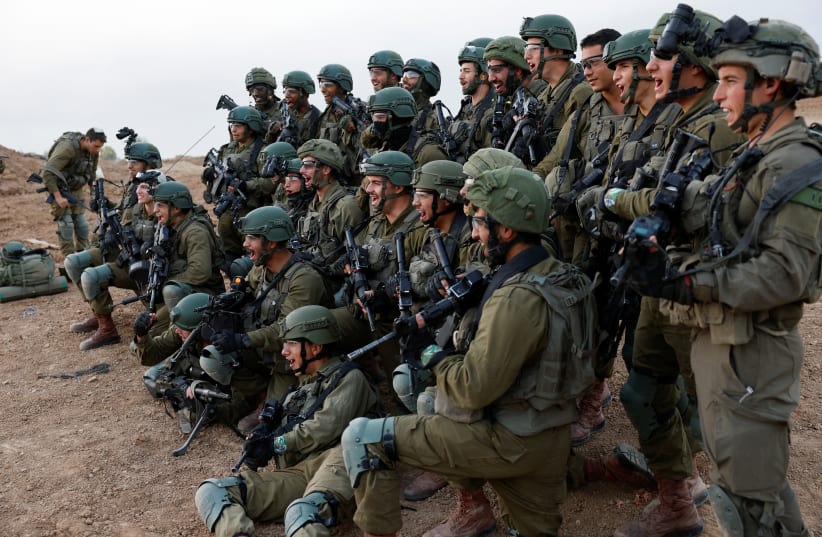  Soldados de las FDI reaccionan mientras posan para una foto de grupo, en medio de la guerra en curso entre Israel y el grupo terrorista palestino Hamás, cerca de la frontera de Israel con Gaza, en el sur de Israel, 4 de diciembre de 2023. (photo credit: AMIR COHEN/REUTERS)