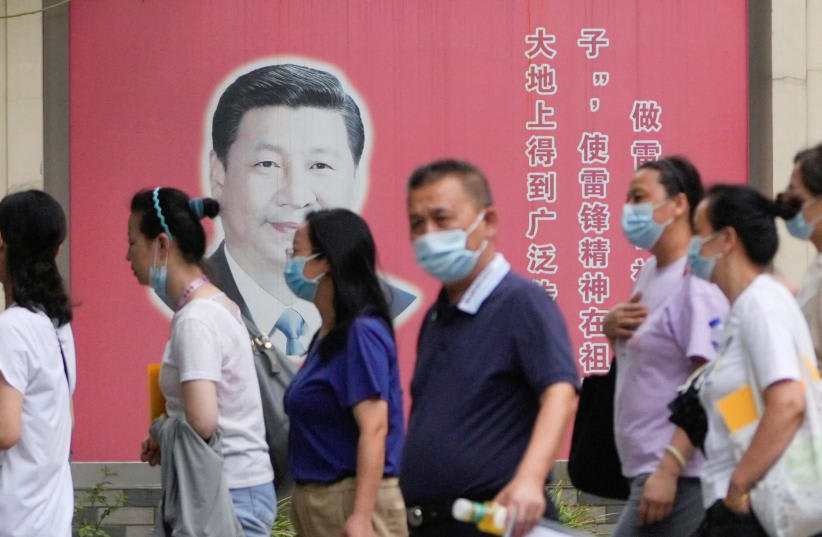  Personas con mascarillas pasan junto a retratos del presidente chino Xi Jinping, tras el brote de la enfermedad por coronavirus (COVID-19), en Shanghái, China, 31 de agosto de 2022. (photo credit: REUTERS/ALY SONG)