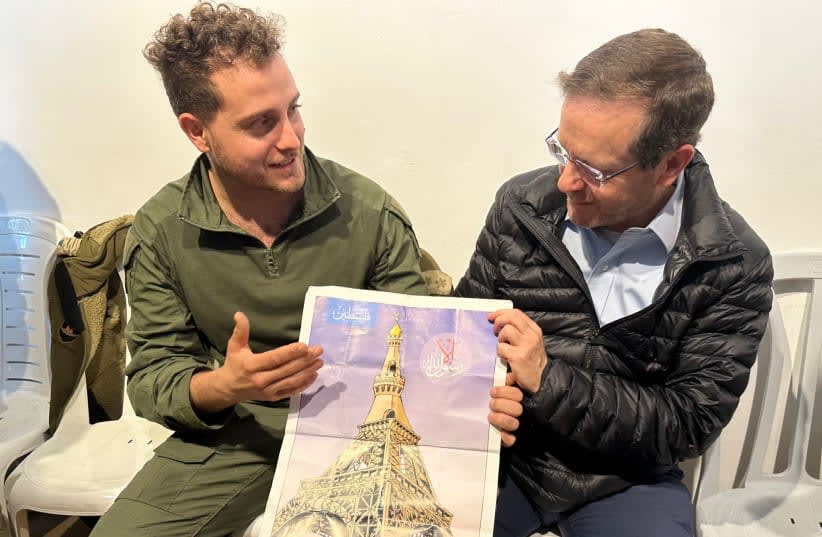  El presidente Isaac Herzog recibiendo un cartel encontrado en Shejaia que muestra la Torre Eiffel como mezquita, el 31 de enero de 2024. (photo credit: GPO)