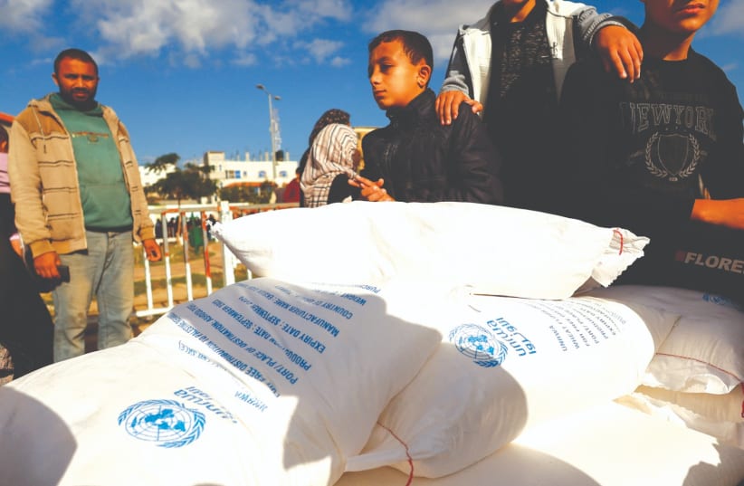  PALESTINIANS RECEIVE flour bags distributed by UNRWA in Rafah, in the southern Gaza Strip last November. (photo credit: IBRAHEEM ABU MUSTAFA/REUTERS)