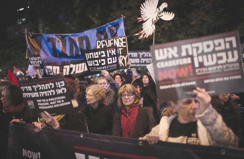  Manifestantes sostienen pancartas pidiendo un alto el fuego en Gaza y un proceso político, en una concentración de protesta en Tel Aviv, el sábado por la noche. La unidad está condicionada, y la condición es que todos sigan el rumbo marcado por el gobierno, argumenta el escritor. (photo credit: ERIK MARMOR/FLASH90)