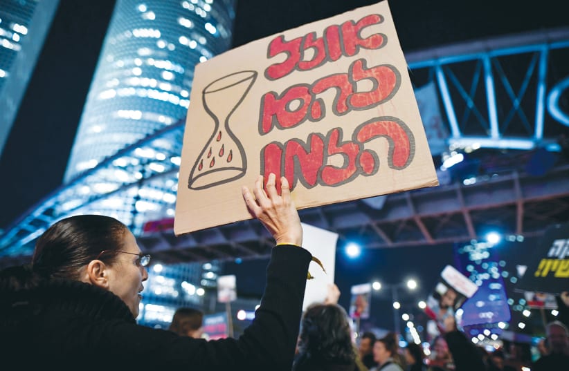  A WOMAN holds up a sign, at a demonstration this past week in Tel Aviv, stating that time is running out to save the hostages. (photo credit: AVSHALOM SASSONI/FLASH90)