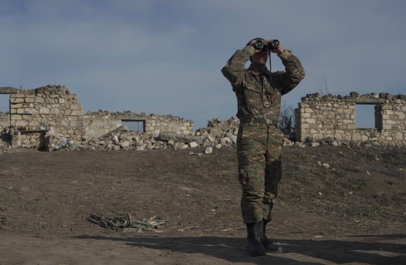  Un soldado de etnia armenia mira a través de unos prismáticos mientras se encuentra en posiciones de combate cerca de la aldea de Taghavard, en la región de Nagorno-Karabaj, el 11 de enero de 2021. (photo credit: REUTERS/ARTEM MIKRYUKOV)