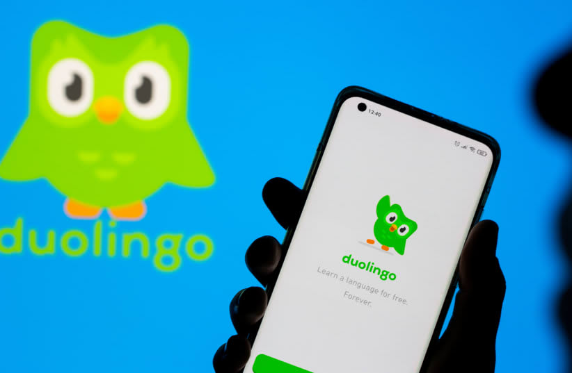  Una mujer posa con su smartphone delante del logotipo de Duolingo en esta ilustración tomada el 29 de junio de 2021. (photo credit: DADO RUVIC/REUTERS)